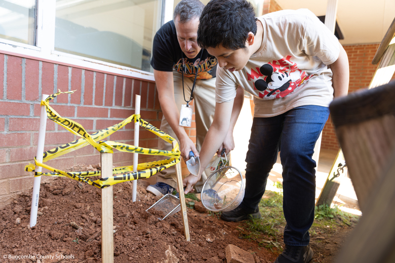 Student and teacher digging in dirt.