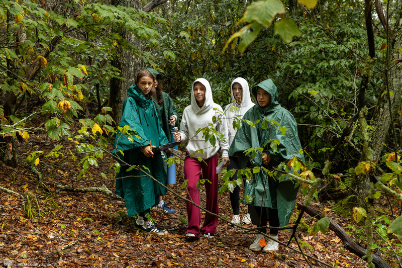 Five students look through the woods.