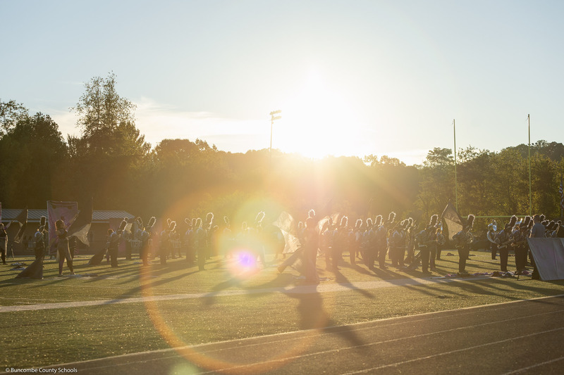 T.C. Roberson High students march while backlit by the sun.