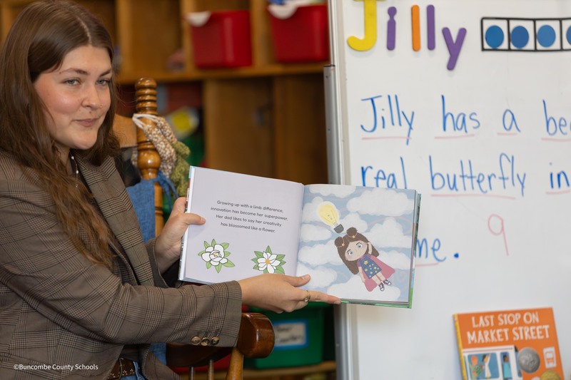 Crenshaw holds book to show students