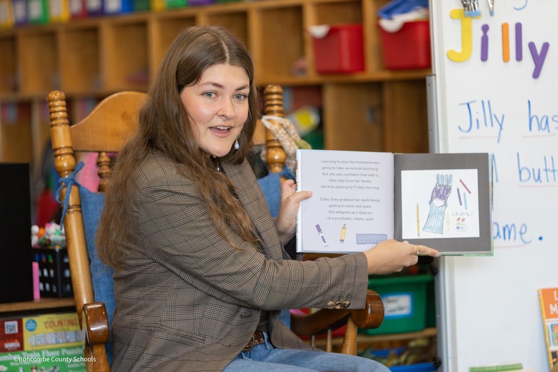Crenshaw holds book to show students