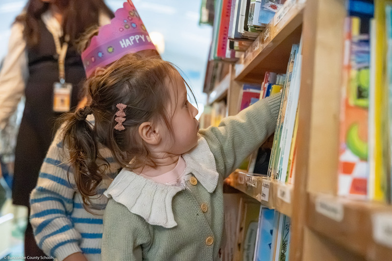 A pre-k student pulls a book from a shelf in the BCS Bookmobile.