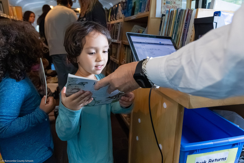 A pre-k student checks out a book in the BCS Bookmobile.