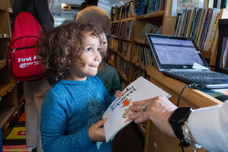 A pre-k student checks out a book in the BCS Bookmobile.