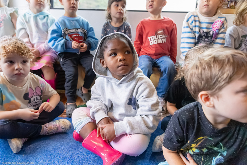 A pre-k student listens as an adults reads inside the BCS Bookmobile.