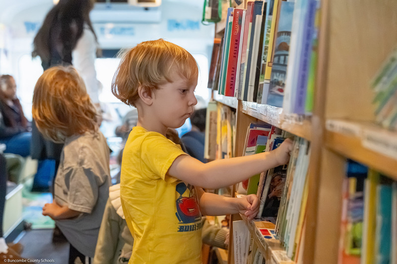 A pre-k student pulls a book from a shelf in the BCS Bookmobile.