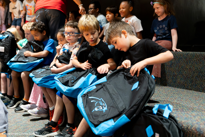 Students looking at their new backpacks.