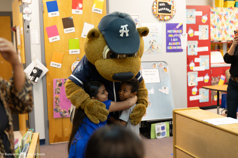 Ted E. giving two students a hug.