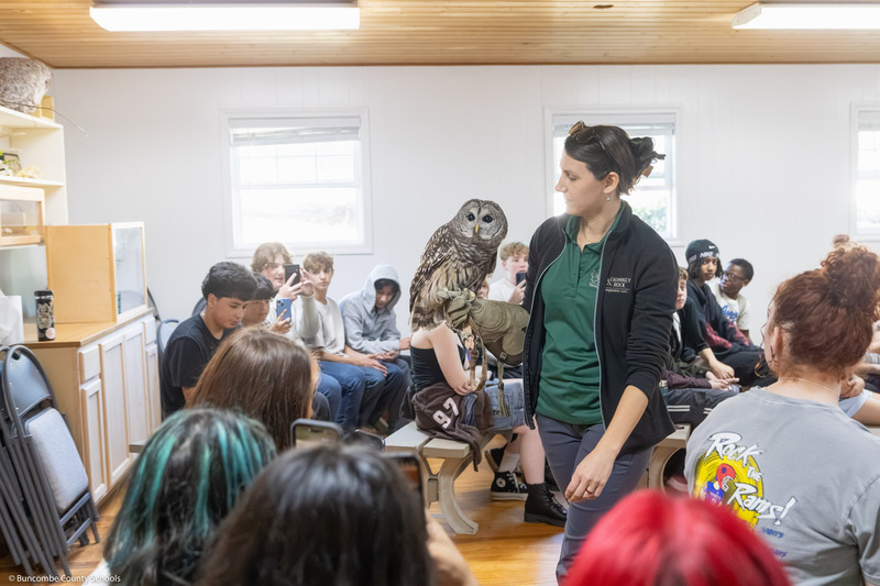 A ranger shows a barred owl to students in the Animal Discovery Den.