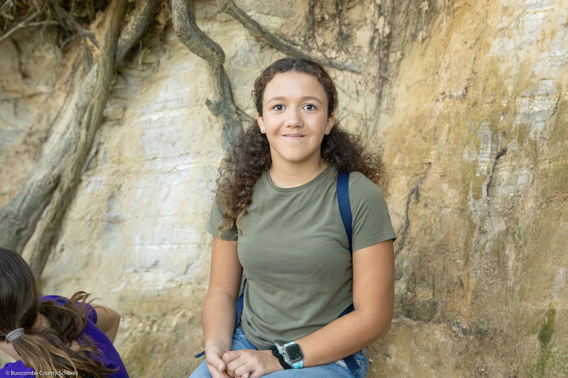 A student smiles while posing in front of a rock formation.