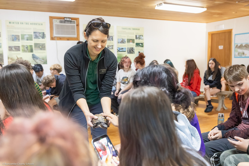 A ranger shows a box turtle to students in the Animal Discovery Den.