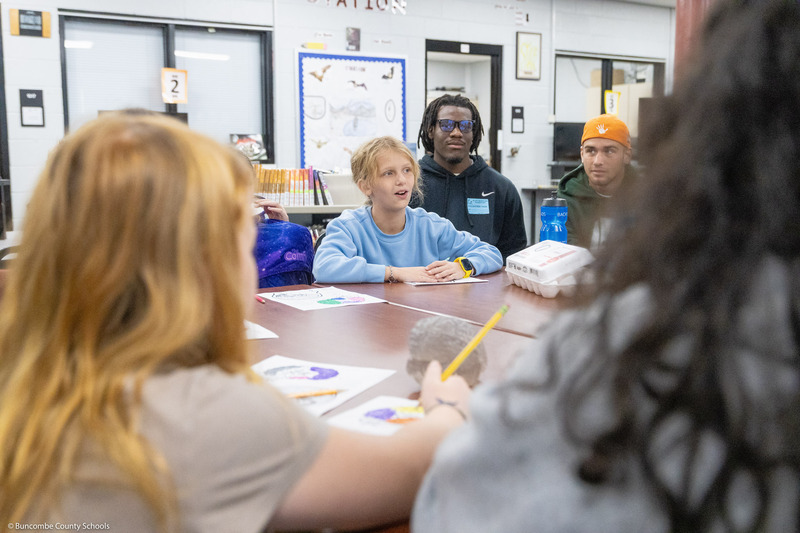 Warren Wilson students sit around a table and lead a project with Black Mountain Elementary students.
