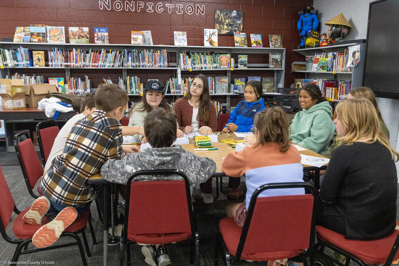 Warren Wilson students sit around a table and lead a project with Black Mountain Elementary students.