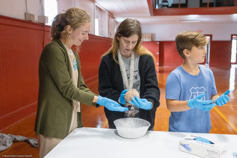 A teacher and college student handle a human brain.