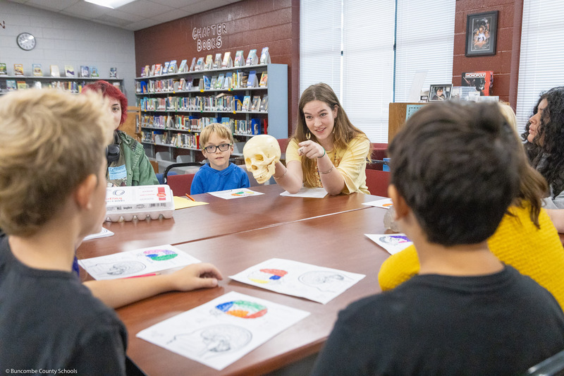 Warren Wilson students sit around a table and lead a project with Black Mountain Elementary students.