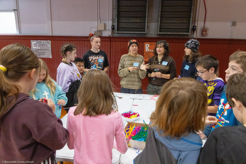 Warren Wilson students sit around a table and lead a project with Black Mountain Elementary students.