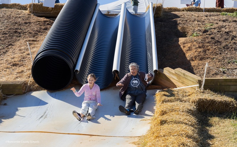 student and teacher race down two slides