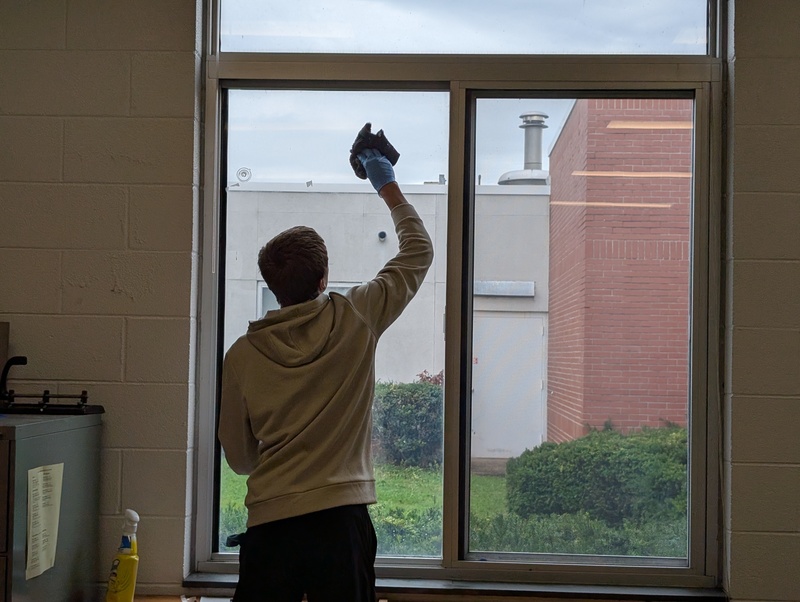 A volunteer uses a cloth to wash a window in the serenity room