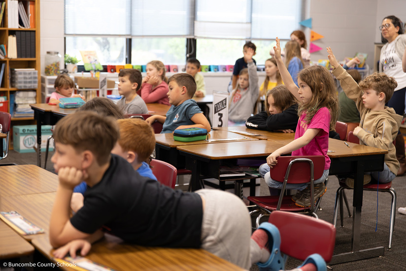 Students raising hands to ask questions. 