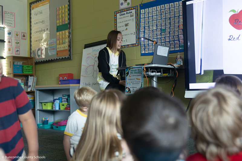 High school student reading her book to the students. 