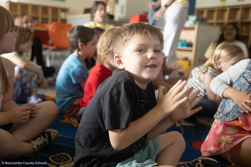 Little boy smiling at the camera and clapping his hands. 