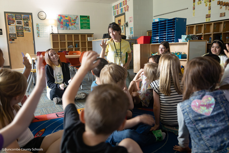 Students raising their hands to ask a question for a high schooler. 