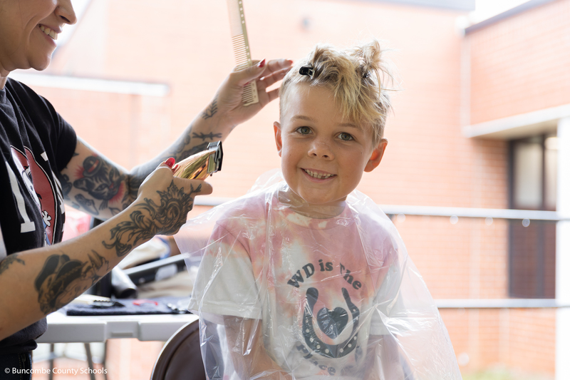 Little boy smiling while getting his haircut. 