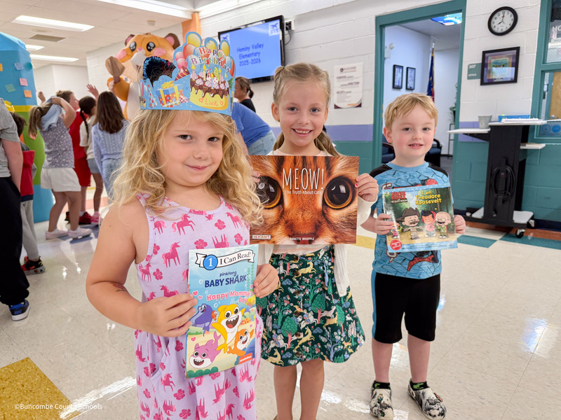 three students holding their new books