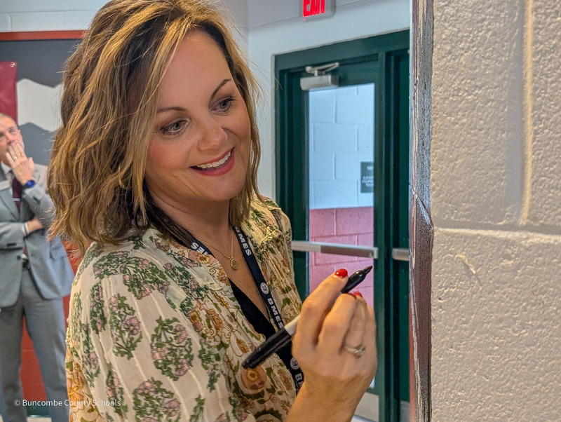 Mrs. Atkins holds a marker, preparing to sign her wall mural