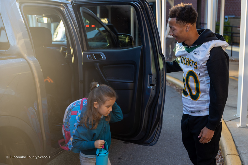 Reynolds football player holds the car door as a Haw Creek student exits the vehicle.