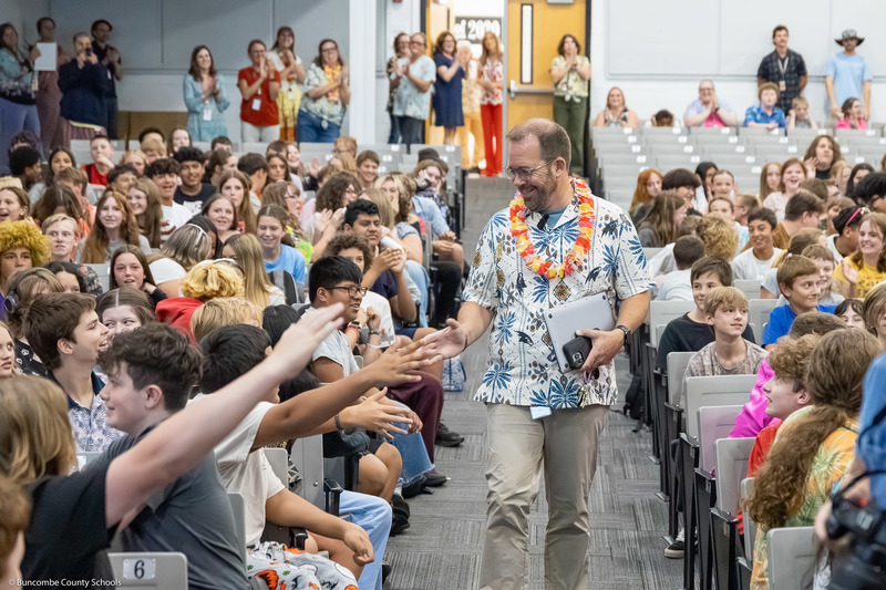 Mr. Honeycutt walks down the aisle, high-fiving students as he approaches the stage