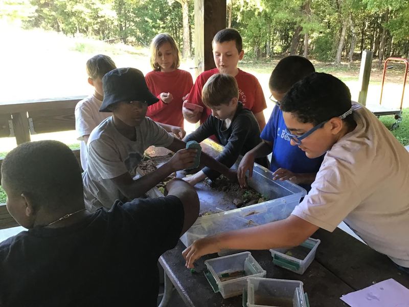 Students doing a hands on activity about erosion with their hands in some dirt. 