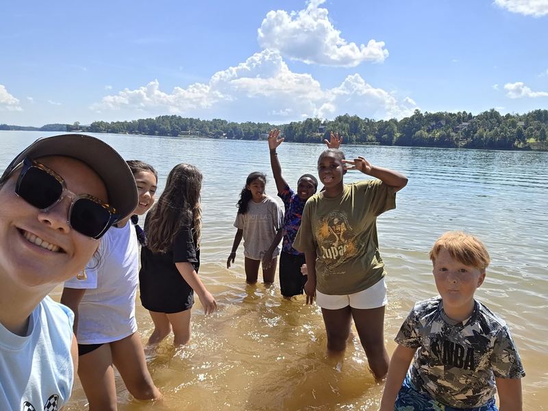Students and teacher standing in the water at Lake James. 