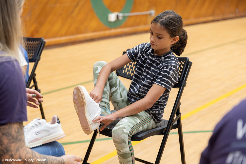 Female student putting a shoe on her foot. 
