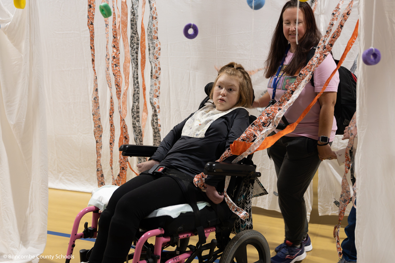Teacher pushing a student in a wheelchair through the corn maze. 