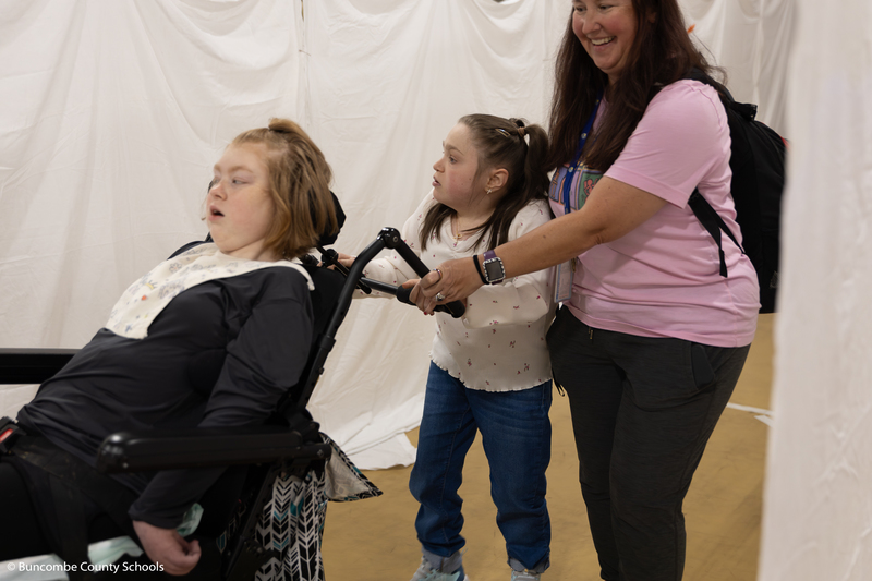Student helping push a student in a wheelchair through the maze. 