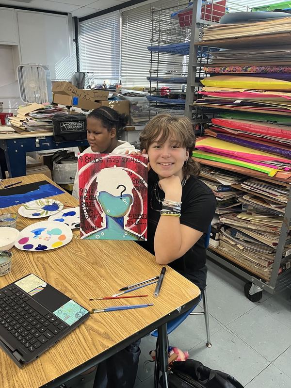 Girl holding up her photo she painted. 