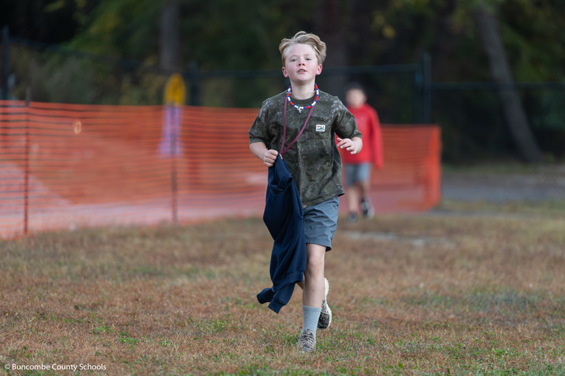 Boy in dark camo shirt and gray shorts running. 
