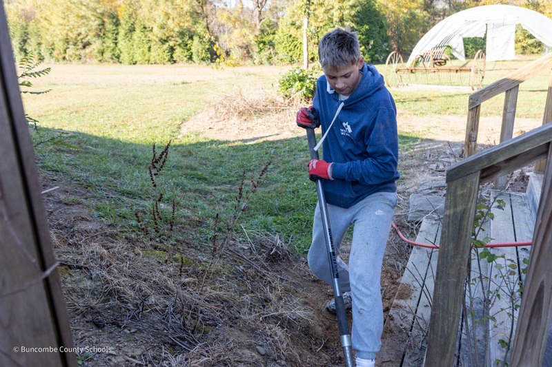 A student digs a hole with a shovel
