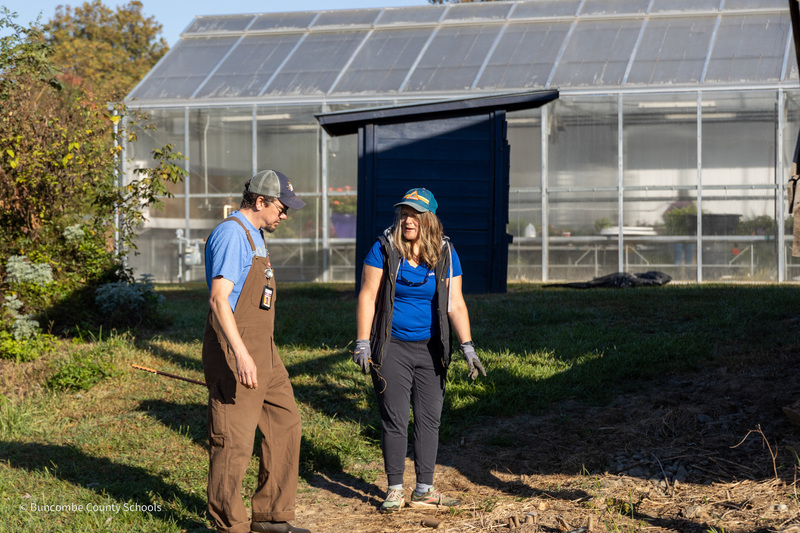 Mr. Foote and a Rotary volunteer stand in front of the greenhouse at Community High.
