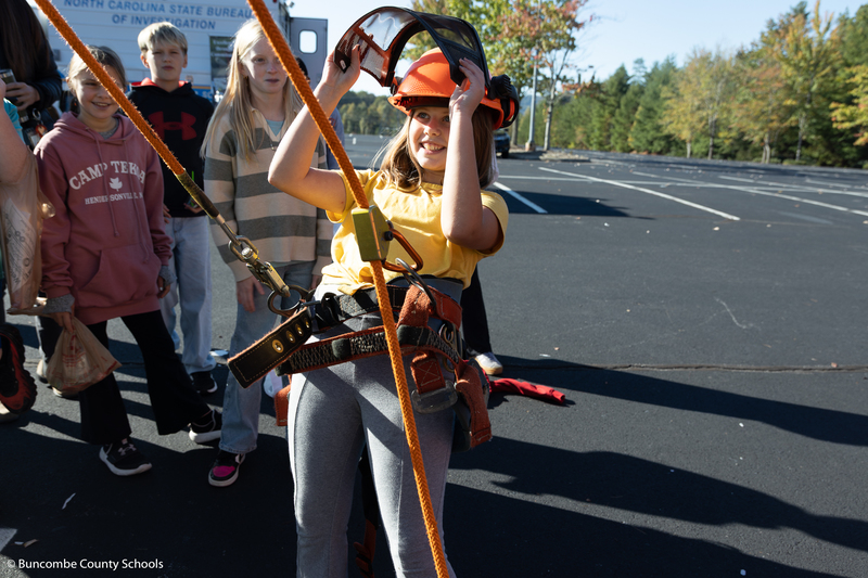 Female student trying on tree climbing gear. 