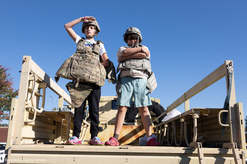 Two male students trying on gear from the Army. 