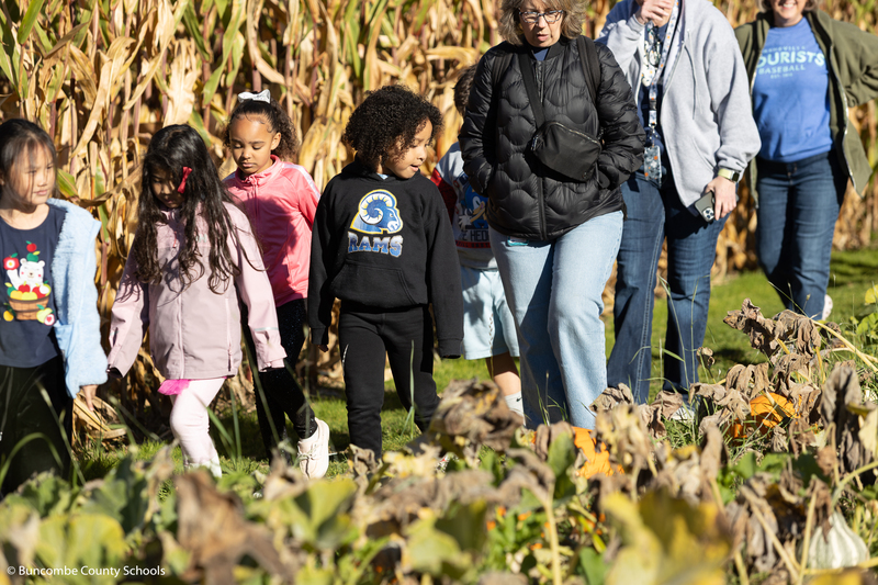 Group of kids and adults walking through the pumpkin patch.