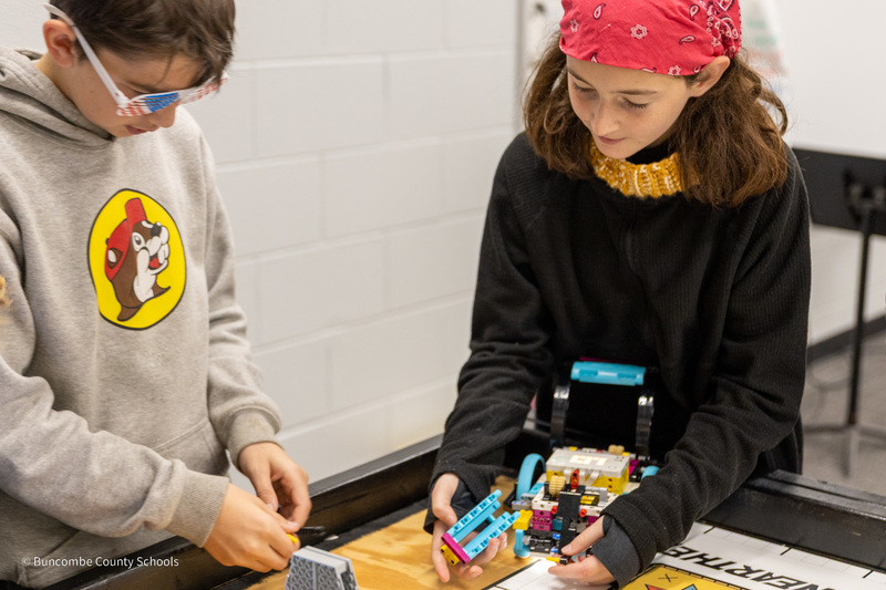 Two students work at building their LEGO robot at the table