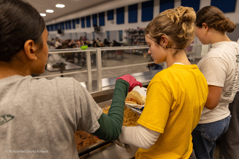 A shot behind students working the serving line at Transformation Village