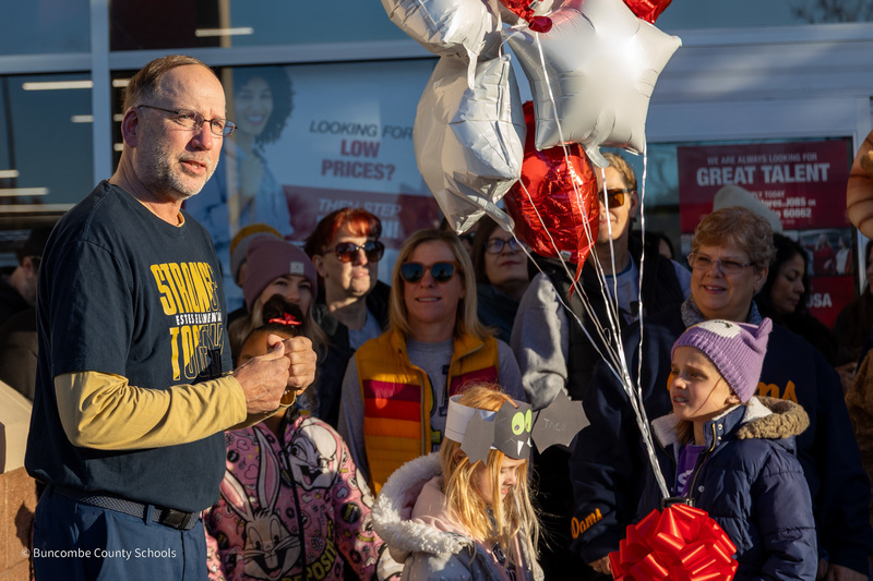 Mr. Dale stands next to students and parents speaking in front of Burlington.