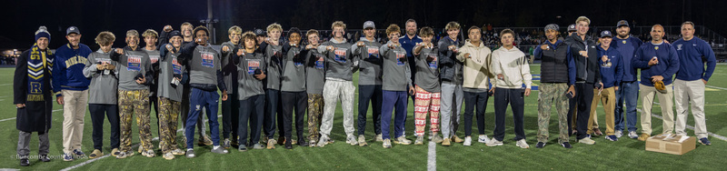 Dr. Jackson and Mr. Allison stand in a line of baseball players on the football field. The players have just received their rings.