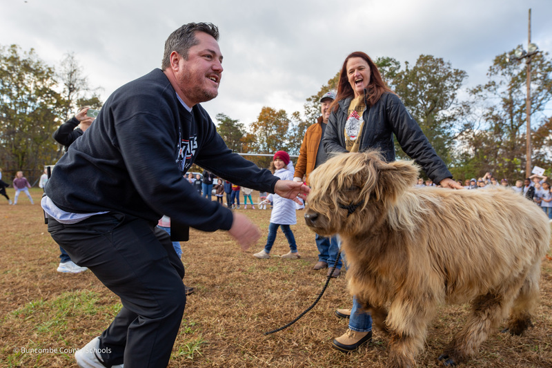 Mr. Harrell stands next to the highland cow