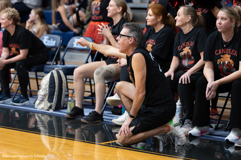 Candler Volleyball team on the sidelines cheering on their teammates who are on the court.