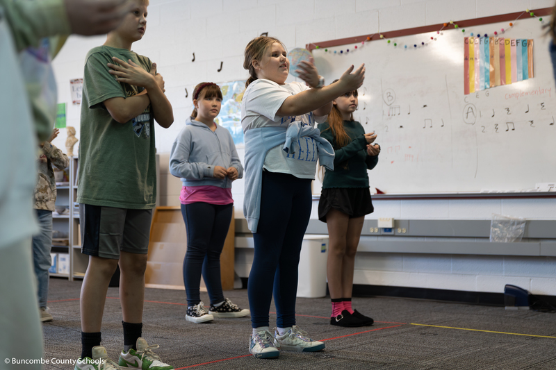 Girl standing and crossing her arms as she is dancing hula.
